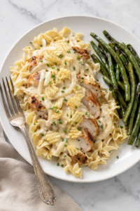 Sliced sour cream and onion chicken with creamy sauce and crushed potato chips served over egg noodles with green beans.