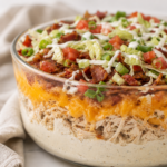 Five layer loaded crack chicken dip topped with bacon, lettuce, diced tomatoes, green onions, and ranch dressing.