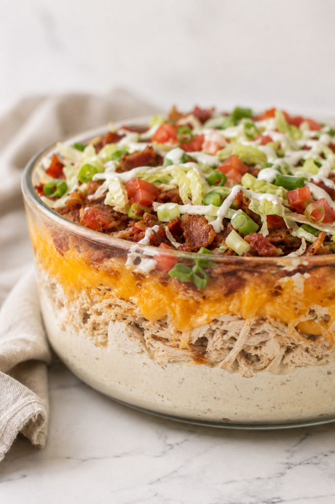 Five layer loaded crack chicken dip topped with bacon, lettuce, diced tomatoes, green onions, and ranch dressing.