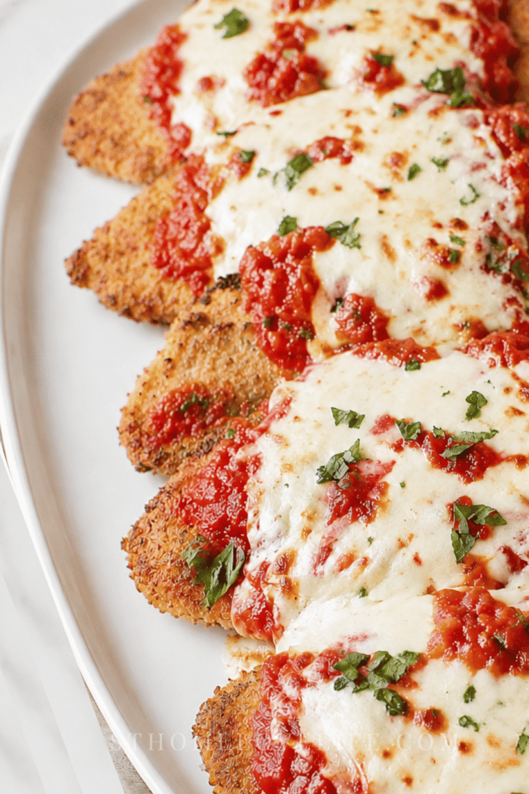 Better than Olive Garden chicken parmigiana with crispy breaded chicken, marinara sauce, and melted mozzarella on a white platter.