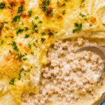 Creamy cowboy butter ground chicken skillet lasagna with melted cheese and golden garlic butter in a dark green enamel skillet