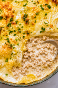 Creamy cowboy butter ground chicken skillet lasagna with melted cheese and golden garlic butter in a dark green enamel skillet