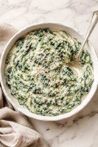 Creamed spinach with nutmeg, Parmesan and black pepper in a white serving bowl