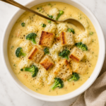 Creamy broccoli cauliflower cheese soup topped with golden garlic croutons and freshly cracked black pepper.