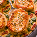 Creamy Tuscan boneless pork chops with spinach and sun-dried tomatoes in a cast-iron skillet