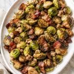 Roasted Brussels sprouts with chestnuts and crispy bacon on a white oval serving platter