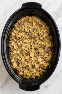 Slow Cooker Hamburger Helper Beef Stroganoff with ground beef, mushrooms and egg noodles in a black crockpot