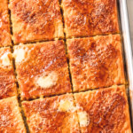 Pumpkin sheet pan pancakes cut into squares and drizzled with melted butter, maple syrup, and cinnamon sugar