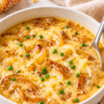 Creamy copycat Outback Walkabout onion soup with caramelized onions, melted cheese, chives, and a silver spoon in a white bowl