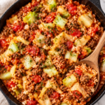 Cabbage roll in a bowl with ground beef, rice, tender cabbage, and tomato sauce in a cast iron skillet with a wooden spoon
