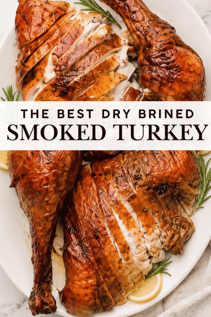 Dry brined smoked turkey sliced and arranged on a white platter with rosemary and lemon