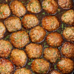 Slow cooker apple cider glazed meatballs in a black Crockpot with a sweet tangy glaze and chopped parsley.