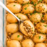 Overhead view of easy baked stuffed onions filled with savory ground beef and rice in a clear glass baking dish.