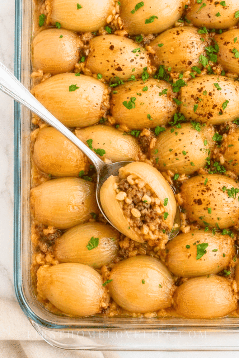 Overhead view of easy baked stuffed onions filled with savory ground beef and rice in a clear glass baking dish.