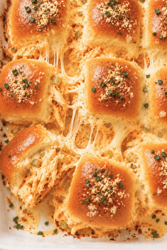 Garlic Parmesan buffalo chicken wing dip sliders with creamy orange chicken filling, melted cheese, celery, parsley, and buttery garlic-Parmesan rolls.