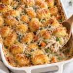Creamy gnocchi chicken pot pie casserole with tender shredded chicken, carrots, celery, peas, Parmesan, and golden potato gnocchi in a white baking dish.