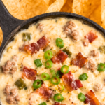 Jalapeño popper bacon hamburger white queso dip in a cast-iron skillet surrounded by tortilla chips