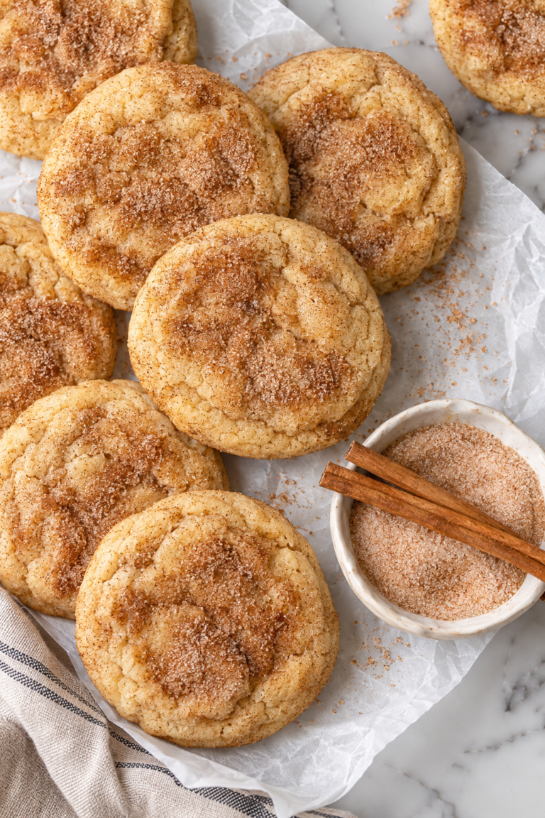 Soft and cakey cinnamon churro cookies coated in cinnamon sugar on parchment paper.
