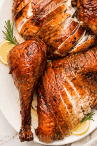 Sliced Thanksgiving smoked turkey with rosemary and lemon on a white platter