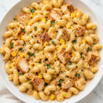 Creamy Cajun chicken pasta with sweet corn, cavatappi, golden chicken pieces, and garlic Parmesan sauce in a white bowl topped with parsley.