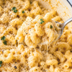 Creamy one pot cacio e pepe mac and cheese in a white Dutch oven with cracked black pepper, fresh parsley, and a spoon scooping up cheesy cavatappi pasta.