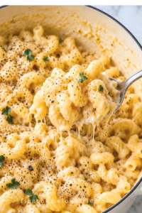 Creamy one pot cacio e pepe mac and cheese in a white Dutch oven with cracked black pepper, fresh parsley, and a spoon scooping up cheesy cavatappi pasta.